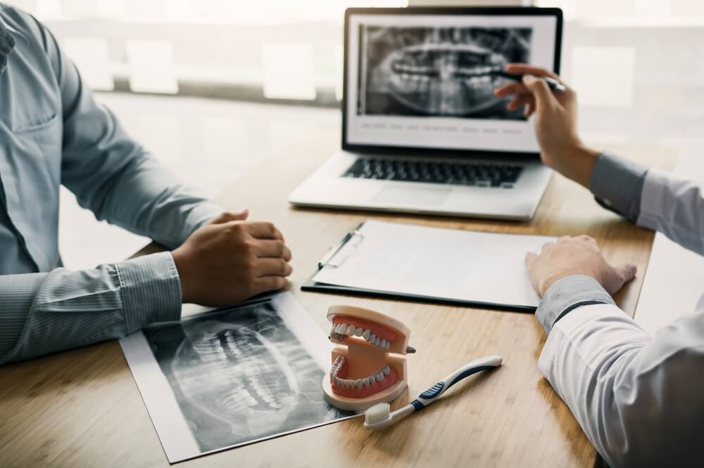 Mesa de planejamento clínico com exames impressos e modelo dental, em composição editorial demonstrativa